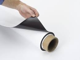 White magnet skin rolled up on a tube with a persons hand peeling back a corner to show the underneath side of the magnet skin being brown in color